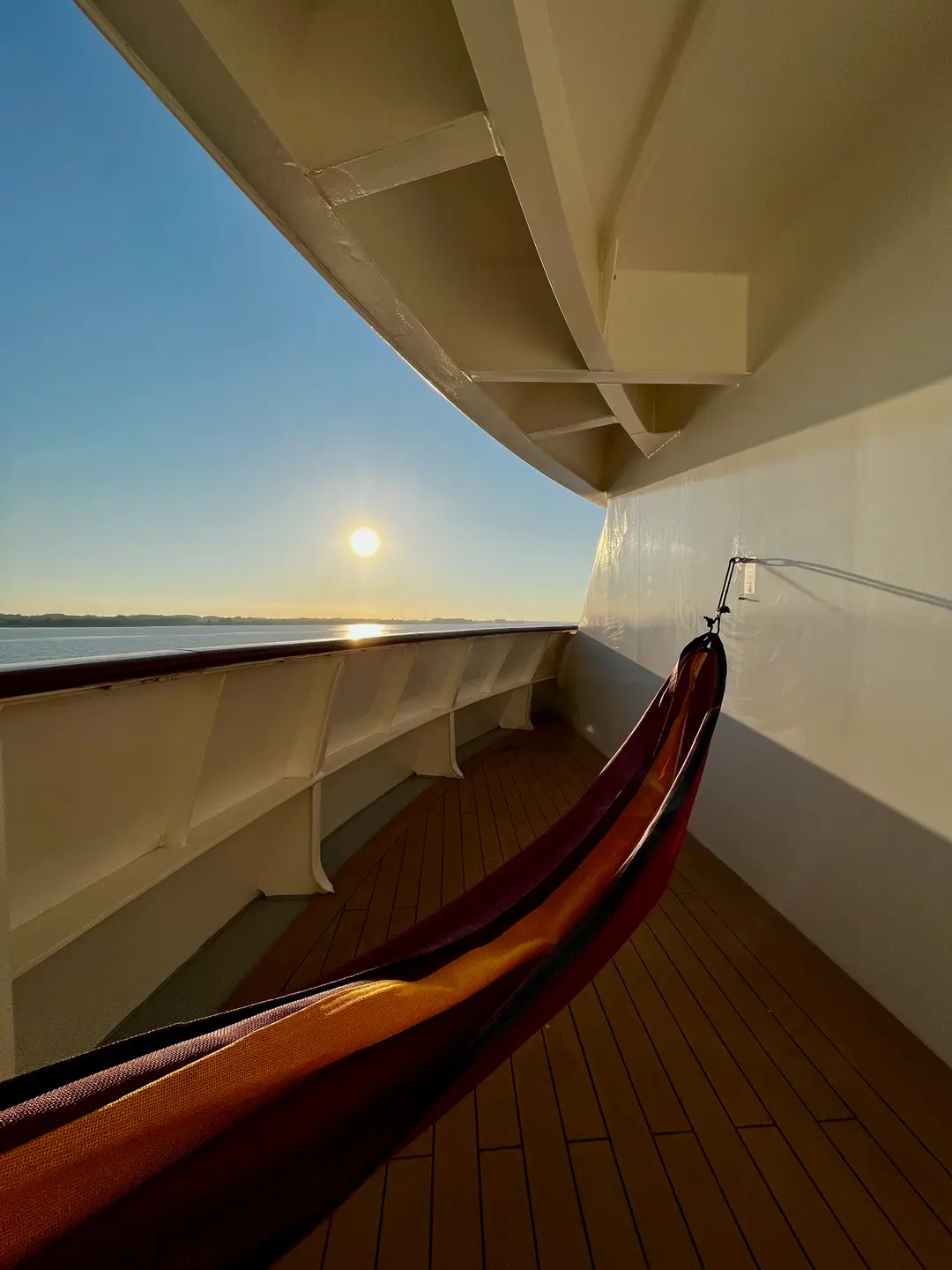 Eine Hängematte auf einem Balkon eines Schiffes im Sonnenuntergang